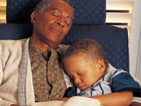 Older man asleep in an armchair holding a sleeping child